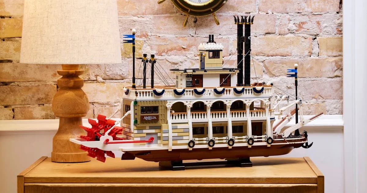 LEGO Ideas River Steamboat 21356 with a red paddle wheel on a wooden dresser in front of a brick wall