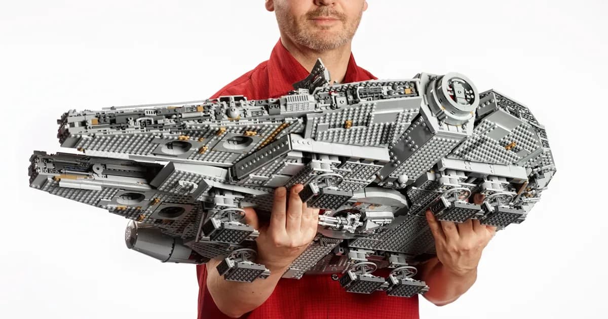 A man in a red shirt holding the finished grey LEGO Star Wars Millennium Falcon 75192 in both arms