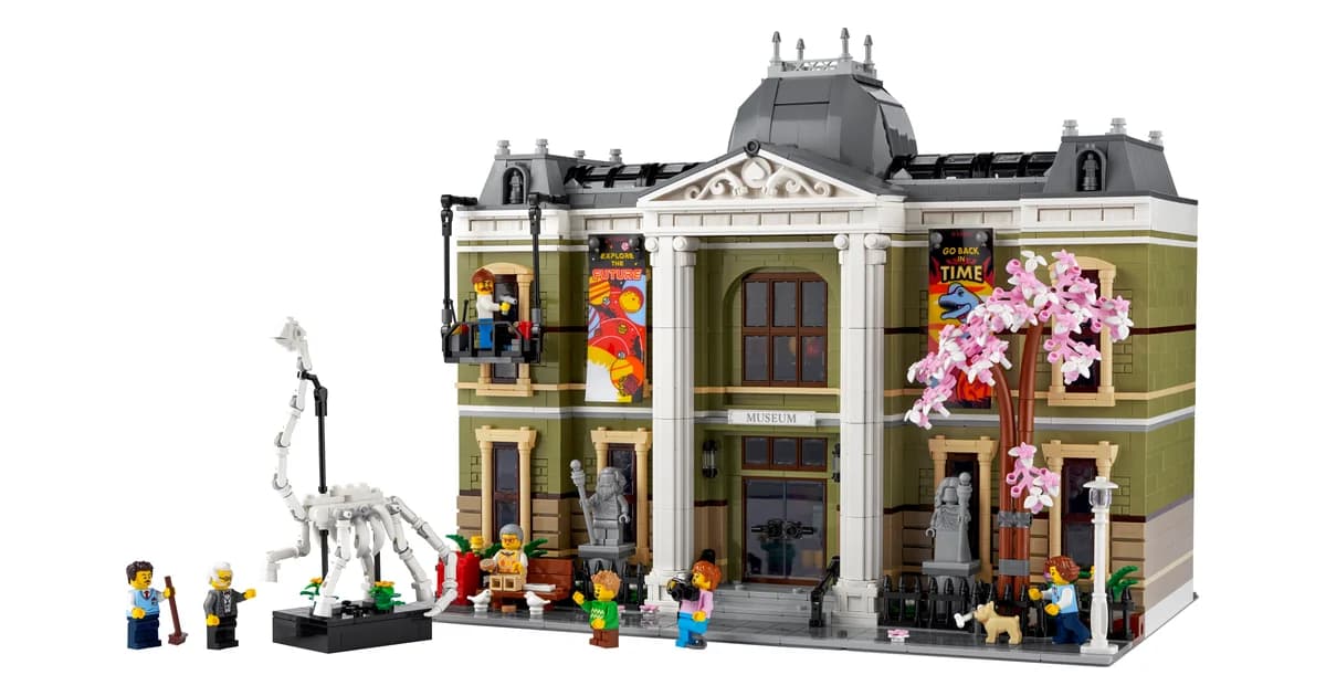 The LEGO Icons Natural History Museum 10326, an olive-green building with white columns, a pink blossom tree and a dinosaur skeleton outside