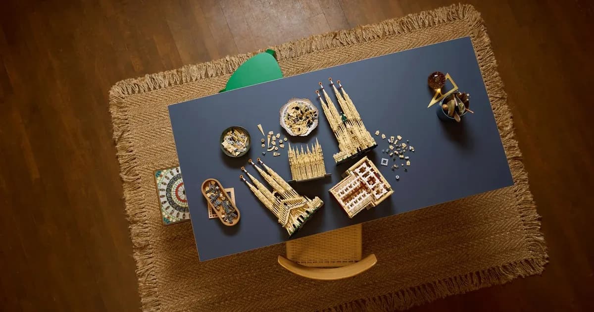 Overhead view of LEGO Sagrada Família sections in progress on a navy table, with trays of tan pieces and spires laid out
