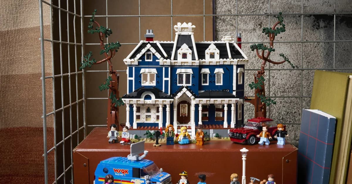 LEGO Stranger Things Creel House on a dark red cabinet in a wire cage, with the blue WSQK van and minifigures in front