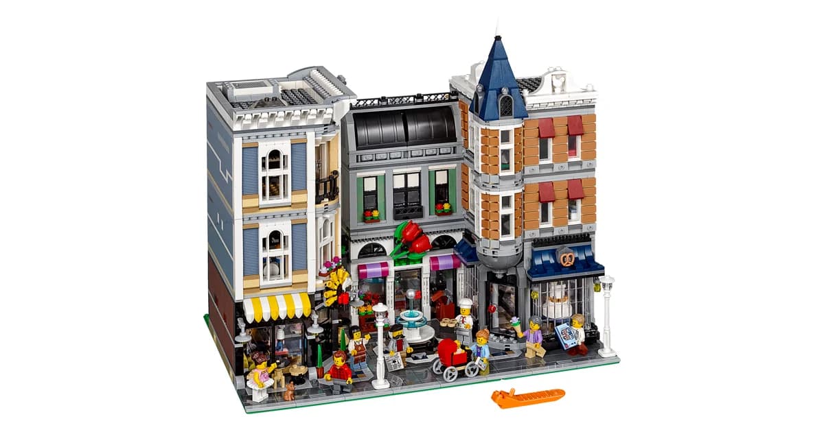 LEGO Assembly Square 10255, three joined modular townhouses with shopfronts and awnings at street level and minifigures on the pavement