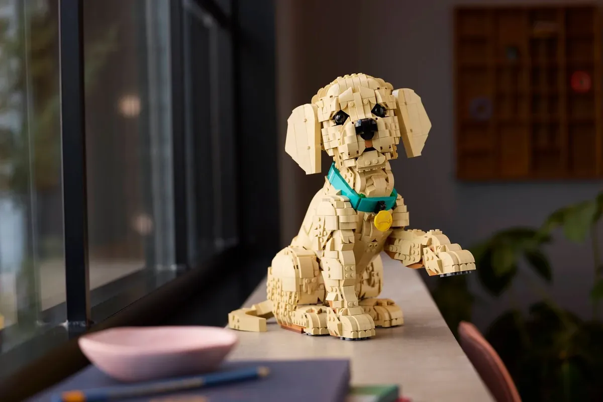 The tan LEGO Golden Retriever Puppy with a green collar sitting on a window sill
