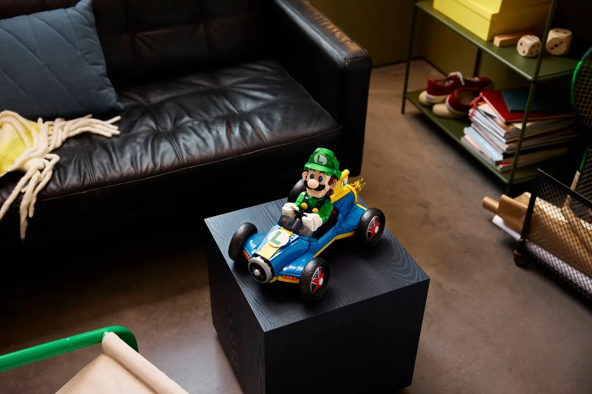 The LEGO Luigi in his blue Mach 8 kart on a black cube beside a leather sofa