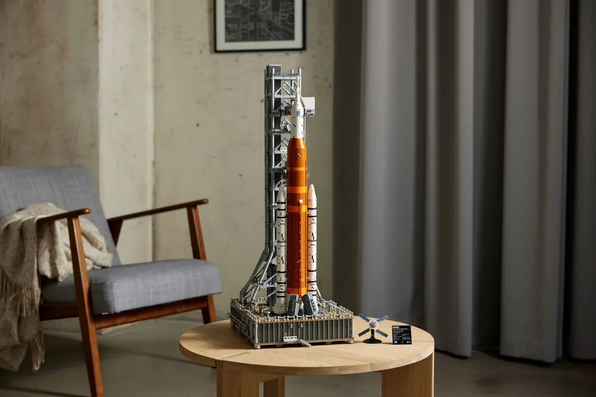LEGO NASA Artemis Space Launch System 10341, orange core stage, white boosters and grey launch tower on a round wooden table