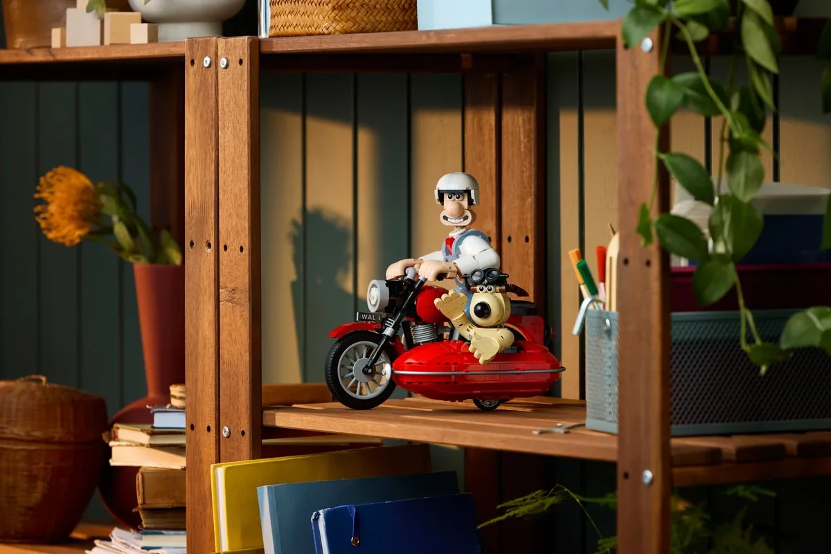 LEGO Ideas Wallace and Gromit 21371: the pair on a red motorbike with a sidecar on a wooden shelf among plants and books