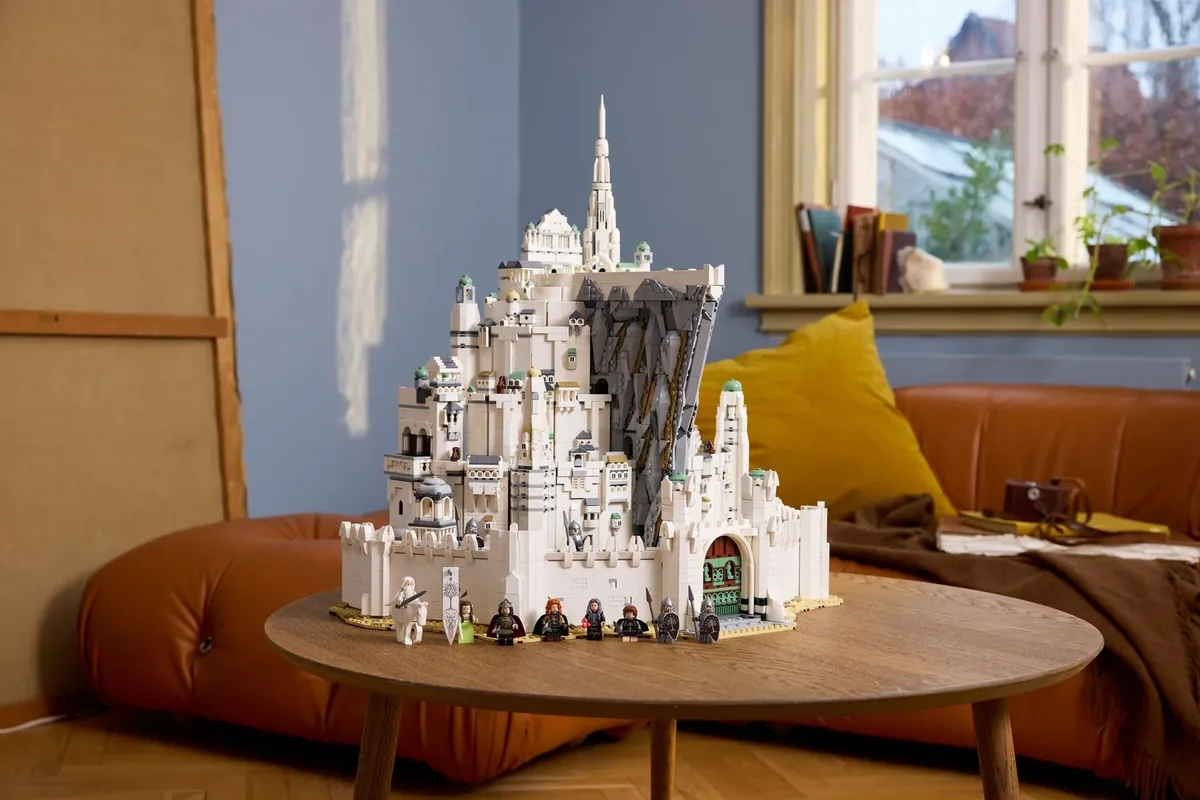 A white LEGO Minas Tirith city model with a tall tower on a round wooden coffee table in a living room