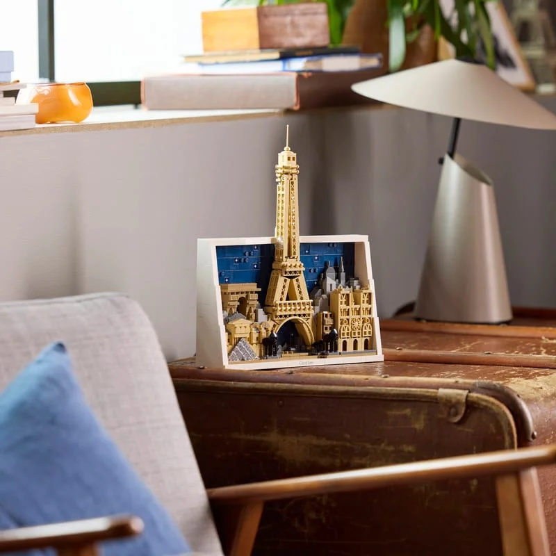 LEGO Architecture Paris City of Love: an Eiffel Tower and Paris rooftops in a white frame on a leather trunk beside a lamp
