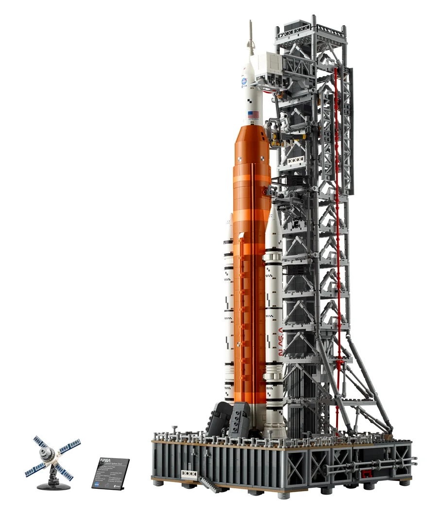LEGO Icons NASA Artemis Space Launch System 10341, an orange and white rocket on a tall grey launch tower with a small crawler and antenna at its base