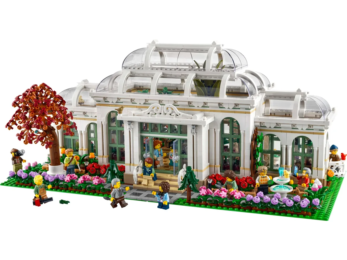 The LEGO Ideas Botanical Garden 21353 complete on white: a white glasshouse with a central dome, a red tree, flower beds and minifigures along the front
