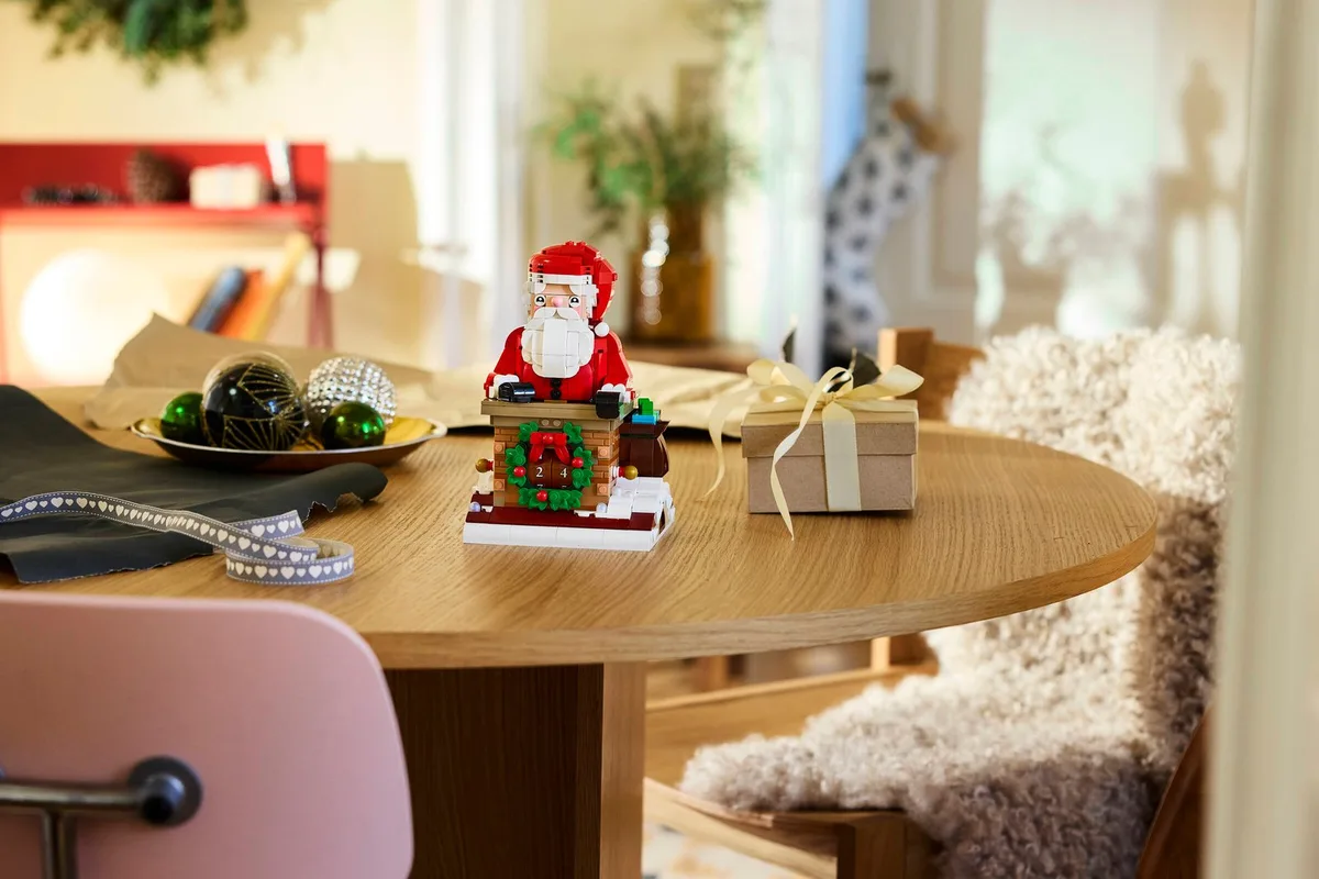 LEGO Santa's Holiday Countdown, Santa climbing out of a brick chimney, on a round wooden table with gifts