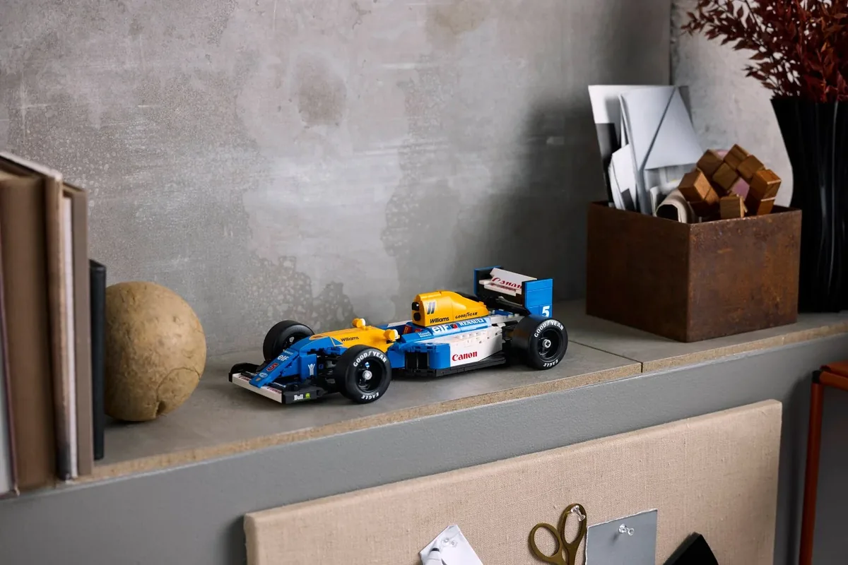 LEGO Icons Williams Racing FW14B 10353 in blue and yellow on a grey shelf beside books and a wooden box