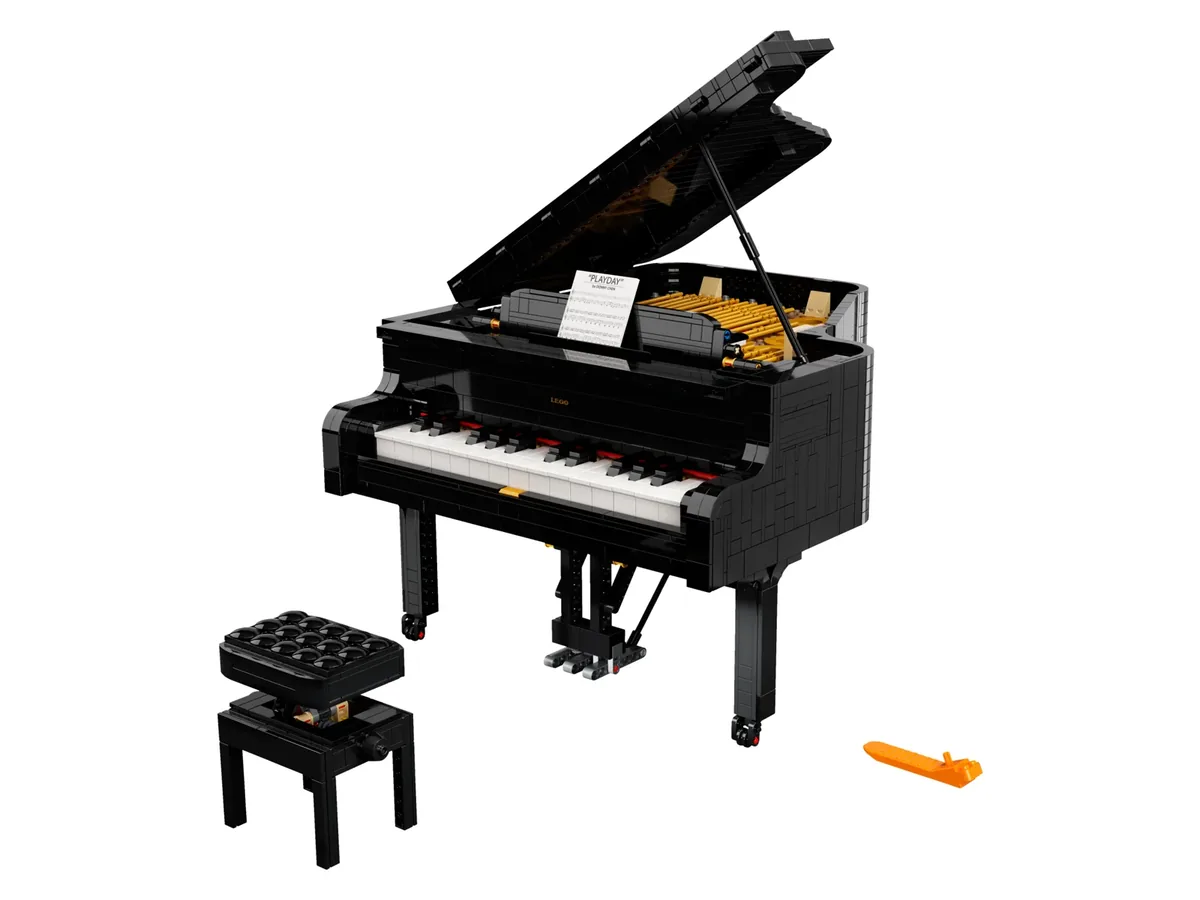 The LEGO Ideas Grand Piano 21323, a black grand piano with its lid raised, a matching stool and a small orange key piece