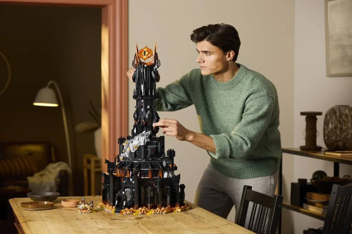 LEGO Lord of the Rings Barad-dûr 10333: a man in a green sweater adjusting the black tower on a wooden table