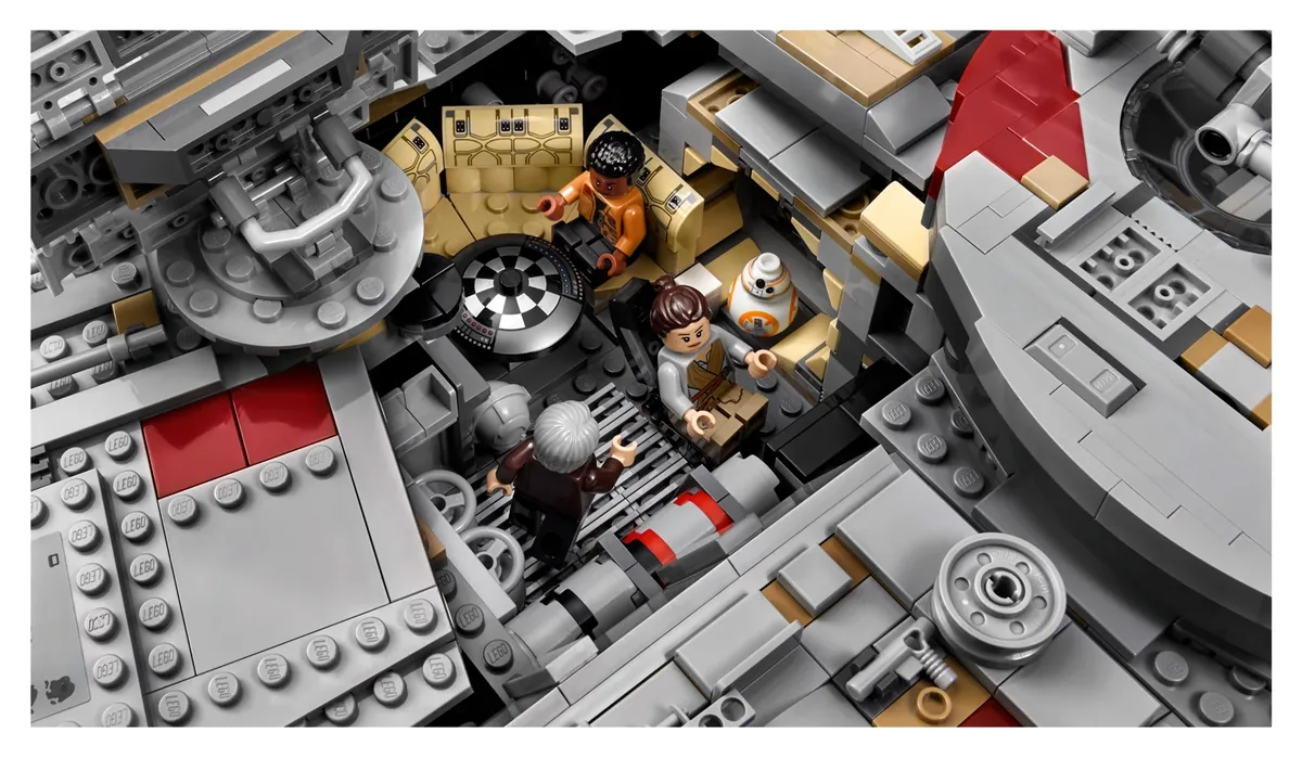 The finished LEGO Millennium Falcon 75192 with a hull panel removed, showing Finn, Rey, older Han Solo and BB-8 around the round game table inside