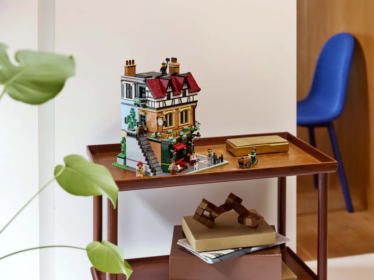 LEGO Icons Tudor Corner 10350 modular building on a wooden trolley beside a monstera leaf and a blue chair