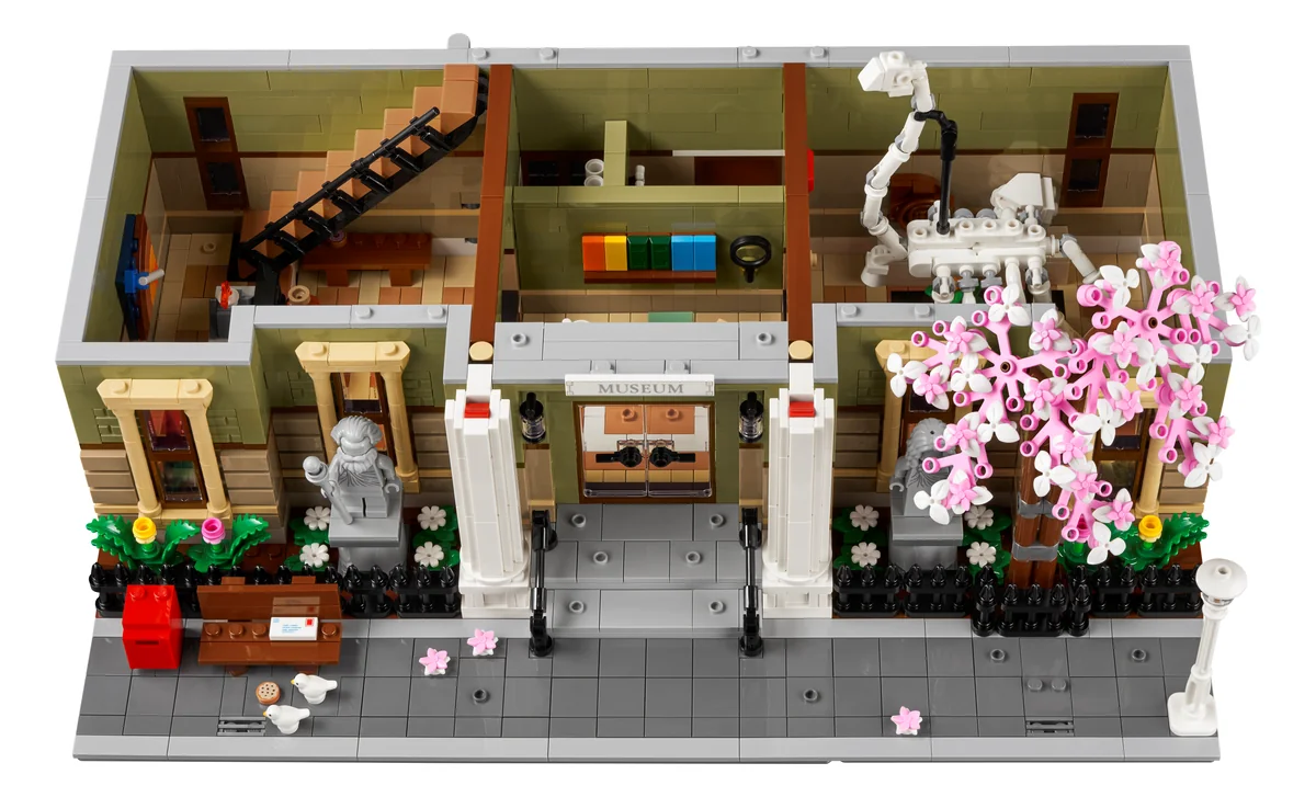 The LEGO Natural History Museum 10326 ground floor opened up, with the brachiosaurus skeleton, a staircase, display cases and a pink blossom tree outside