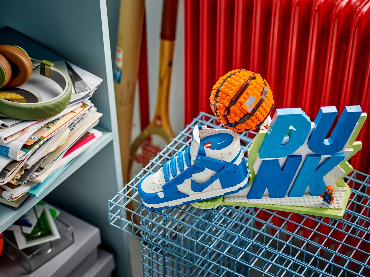 LEGO Nike Dunk sneaker in blue and white with an orange brick basketball and blue DUNK letters on a wire shelf