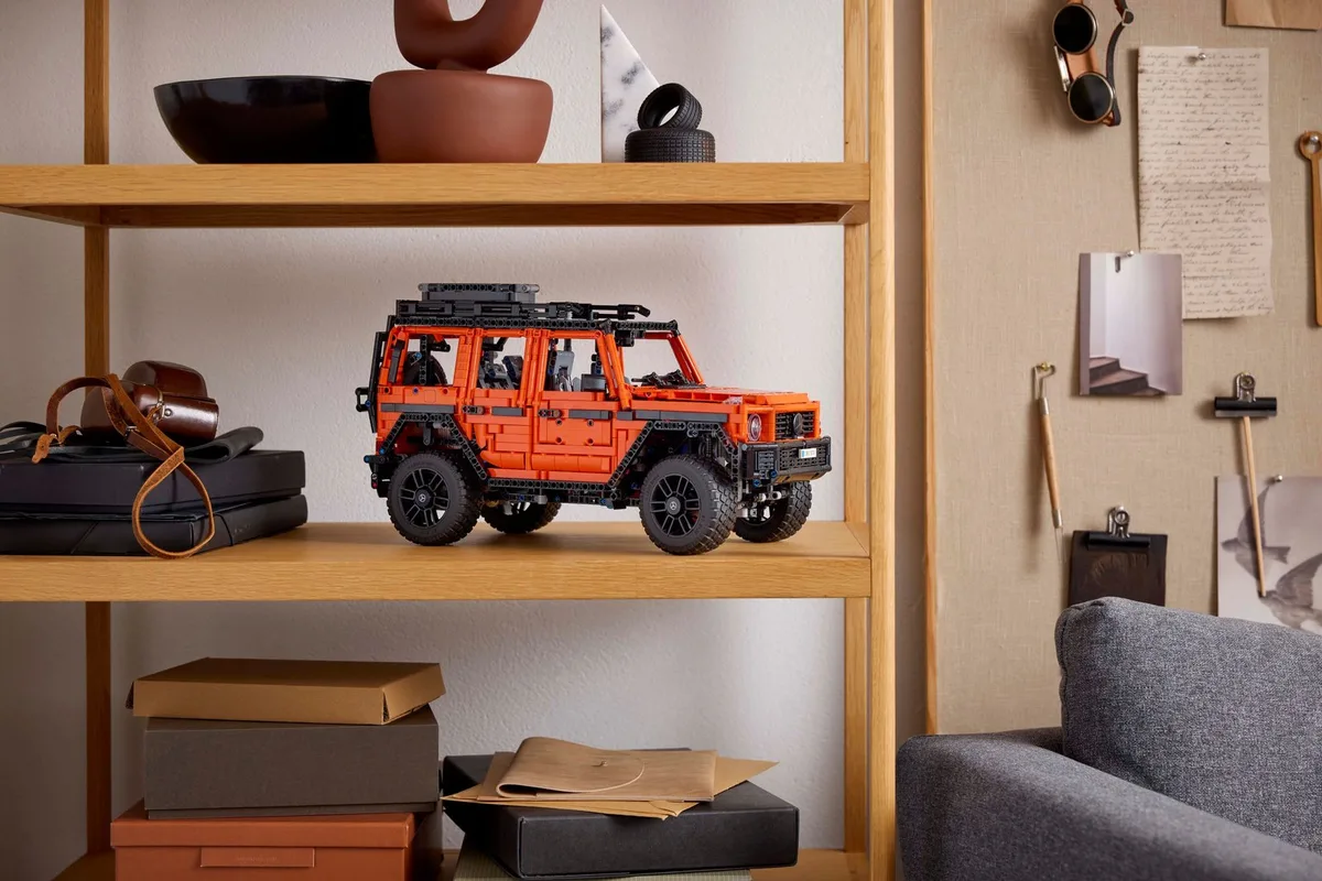 The orange LEGO Technic Mercedes-Benz G 500 PROFESSIONAL Line with a black roof rack, on a wooden shelf