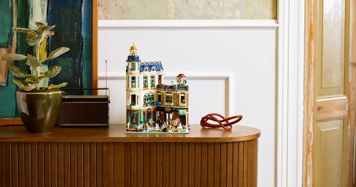 LEGO Icons Shopping Street 11371 modular building on a wooden sideboard beside a potted plant and a radio
