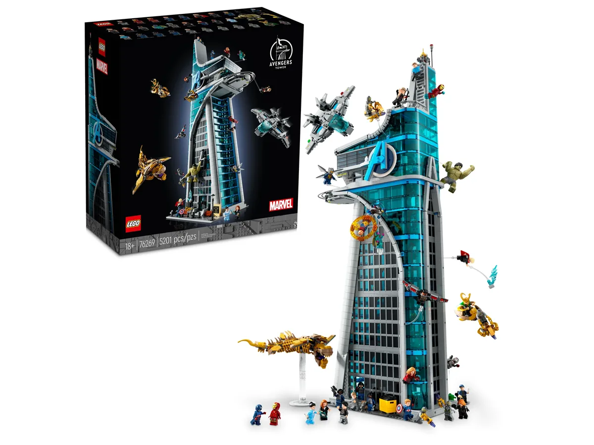 LEGO Marvel Avengers Tower 76269 next to its box, a tall blue-glass tower with the Avengers logo and flying vehicles around it