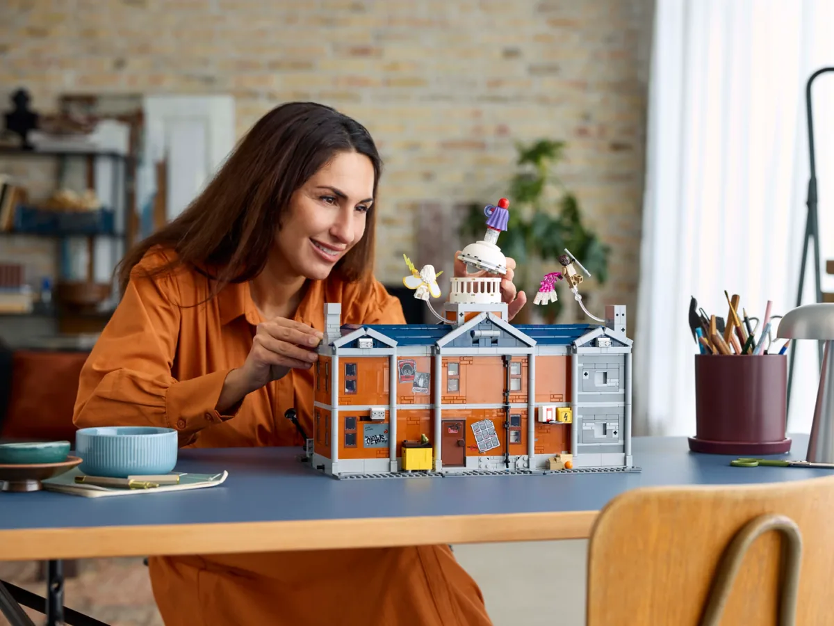 A woman at a table fitting the domed tower onto the LEGO X-Mansion 76294 model