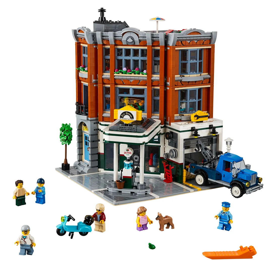 LEGO Corner Garage 10264, a brick-red corner building with a garage and green awning at street level, a blue tow truck and minifigures
